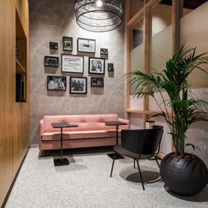 Ontspanningsruimte met roze bank, fotowand en natuurlijke verlichting – sfeervolle en impactvolle invulling van een rustplek binnen de werkplek.