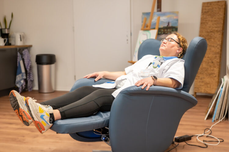 Een medewerker van Zorggroep Amsterdam Oost Flevohuis komt tot rust in de Re-load ontfocus-stoel tijdens een pauze.