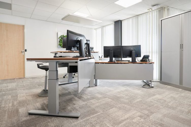 Dubbele werkplekopstelling met zit-sta bureaus en monitorarmen – ergonomische projectinrichting gericht op dynamisch werken.
